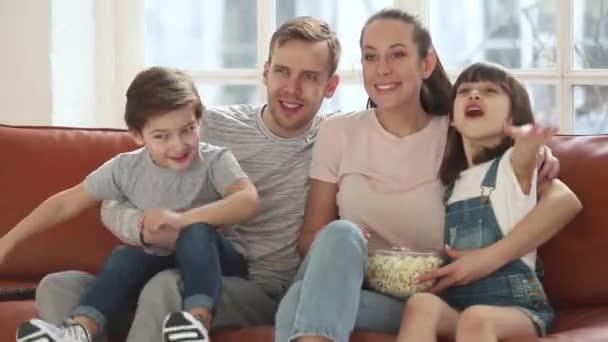 Excitados fãs de futebol da família assistindo esporte jogo de tv celebrando objetivo — Vídeo de Stock