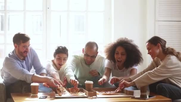 Šťastní různí přátelé baví mluvit jíst pizzu společně — Stock video