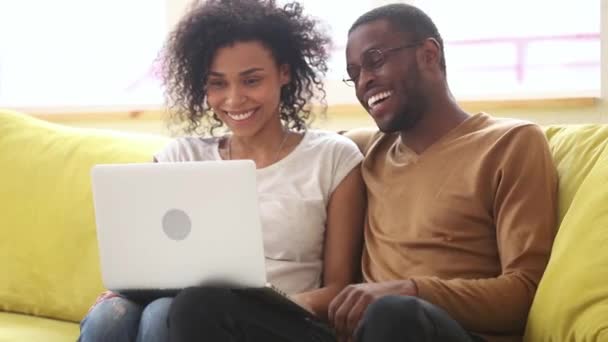幸せなアフリカの若いカップル笑っている話を使用してノートパソコンでホーム — ストック動画