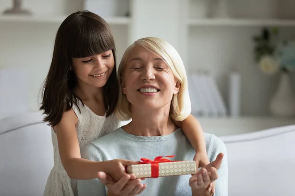 Grand-mère les yeux fermés profiter moment de recevoir un cadeau de la petite-fille — Photo