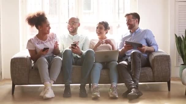 Multikulturella unga studenter skrattar och pratar om att ha roligt med digital teknik — Stockvideo