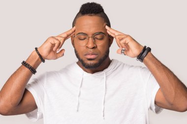 Sinirli Afrikalı Amerikalı adam şakaklara dokunuyor, baş ağrısını hafifletiyor.