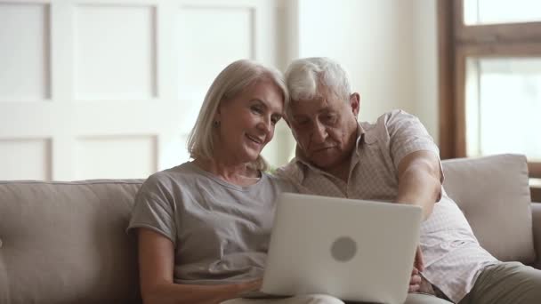 Happy old family couple talking using laptop sit on sofa — Stock Video