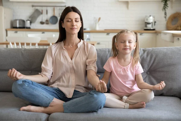 健康的母亲和小女儿在沙发上做瑜伽运动 — 图库照片