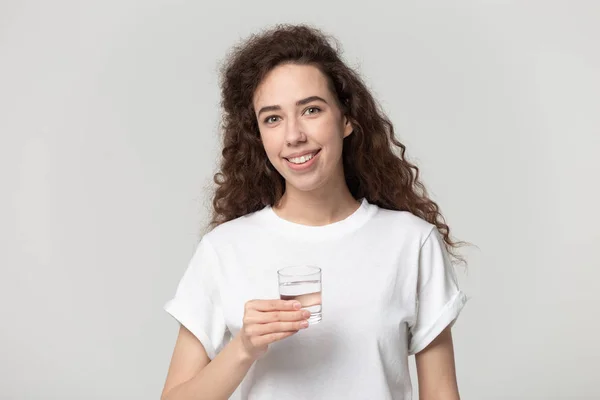 Glimlachende jonge vrouw kijken naar camera met zuiver water glas — Stockfoto