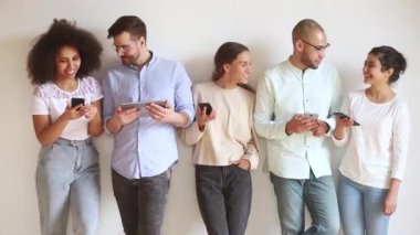 Mutlu çeşitli genç arkadaşlar sıraya girin ve telefon kullanın.