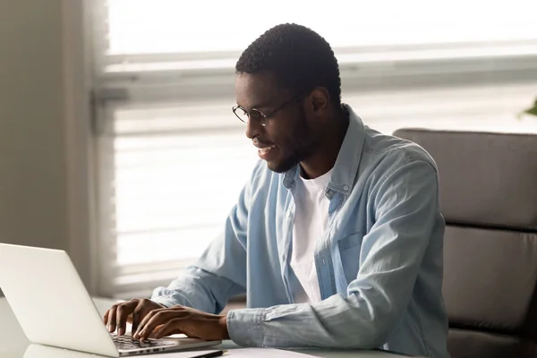 Smiling biracial male employee texting using laptop — ストック写真