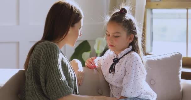 Vårdande mamma pratar med skolbarn dotter sitta på soffan — Stockvideo