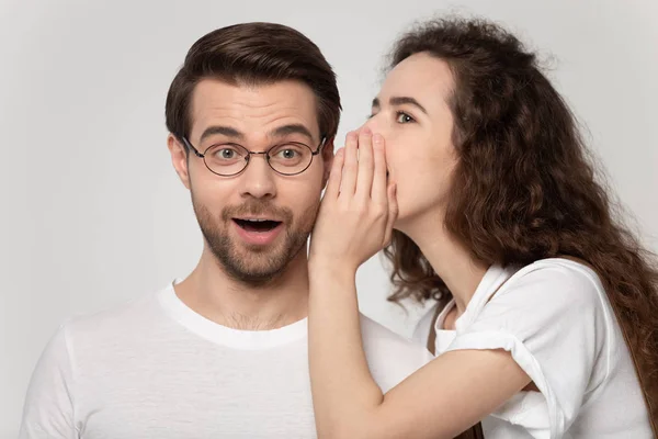 Millennial ragazza sussurrare segreto in stupito fidanzato orecchio — Foto Stock