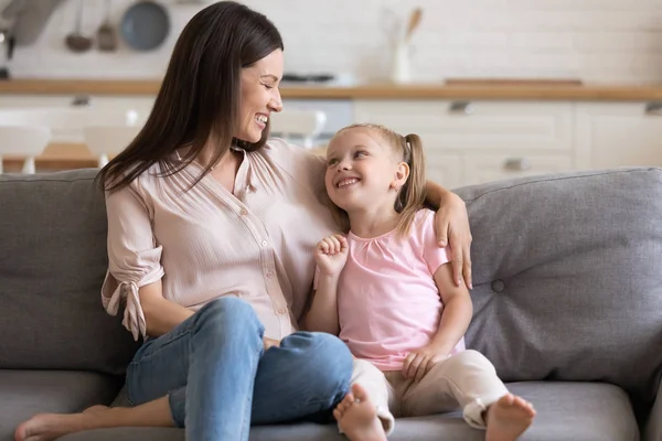 Feliz joven madre adulta e hija pequeña hablando en el sofá — Foto de Stock