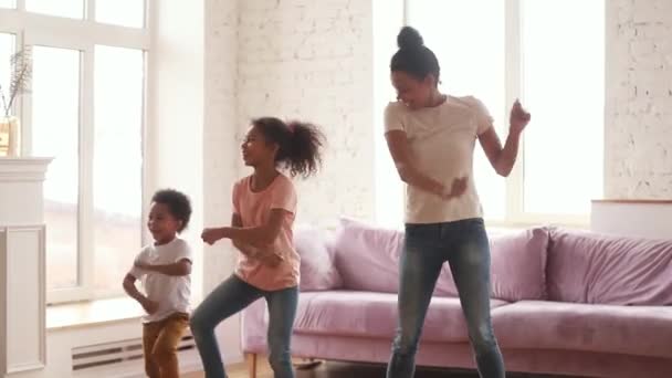 Активна афроамериканська мама і діти танцюють у вітальні — стокове відео