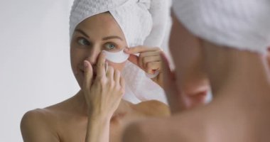 Mutlu 30 'lu yaşlardaki kadınlar banyodaki aynaya göz bandı yapıştırır.