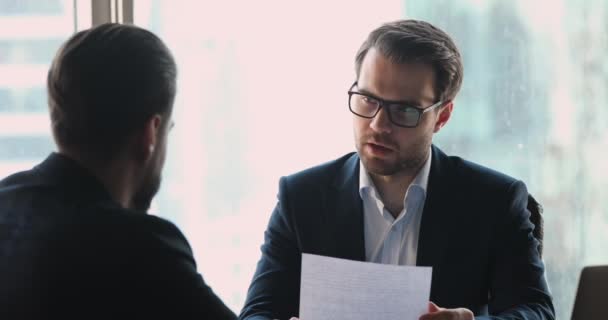 Empleador serio empresario celebración de cv entrevistando solicitante de empleo masculino — Vídeo de stock