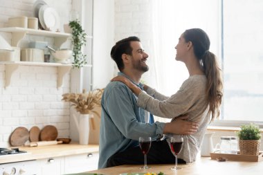 Modern mutfakta şarap içip muhabbet eden mutlu genç çift.