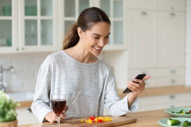 Mutlu bayan elinde telefonla sebze yemeği hazırlıyor. Vegan yemek tarifi.