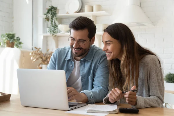 Счастливая молодая пара оплачивает счета онлайн в компьютерном приложении — стоковое фото