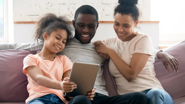Feliz família biracial com a criança assistir vídeo em tablet — Fotografia de Stock
