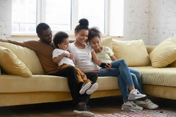 Familia birracial feliz con niños usando el teléfono celular juntos —  Fotos de Stock