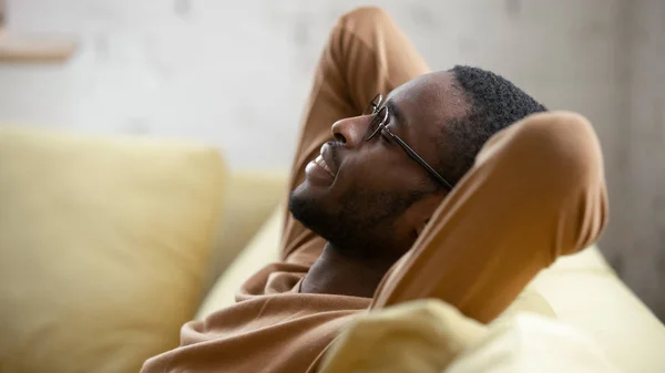 Afro-Amerikalı adam oturma odasındaki rahat koltukta dinleniyor. — Stok fotoğraf
