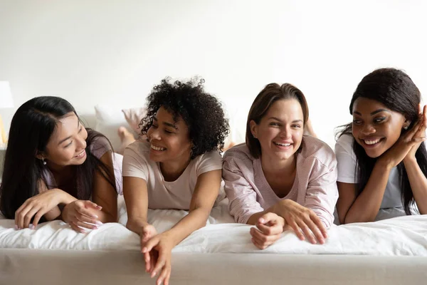 Feliz diversas jovens senhoras relaxar na cama desfrutar de festa de pijama — Fotografia de Stock