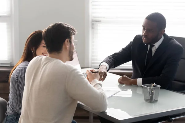 Happy couple closing deal at biracial male agent office — Stock Photo, Image