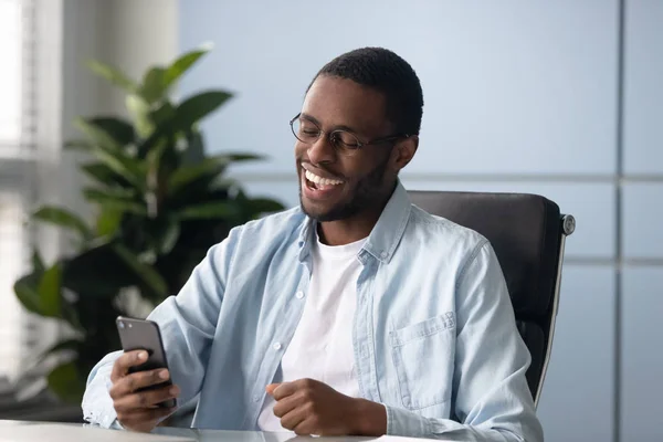 Smiling african American male excited with good news on cell