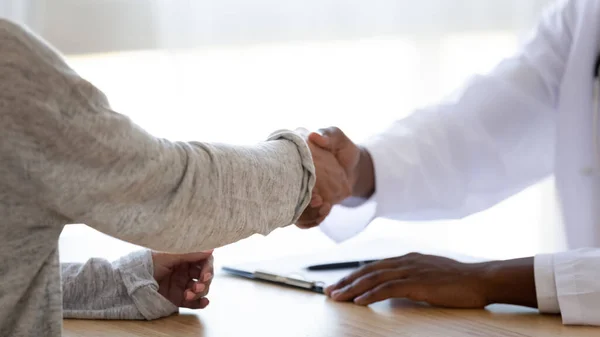 Närbild afrikansk amerikansk läkare skakar hand med ung kvinna. — Stockfoto