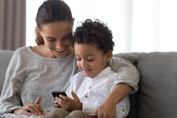 Felice giovane madre che abbraccia il figlio utilizzando applicazioni educative su smartphone . — Foto Stock