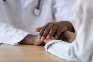 Afrikalı Amerikalı erkek doktorun elini tutan genç kadın, yakın plan..