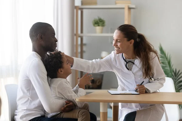 Leende kvinnlig barnläkare stroke huvud söt liten förskola patient. — Stockfoto