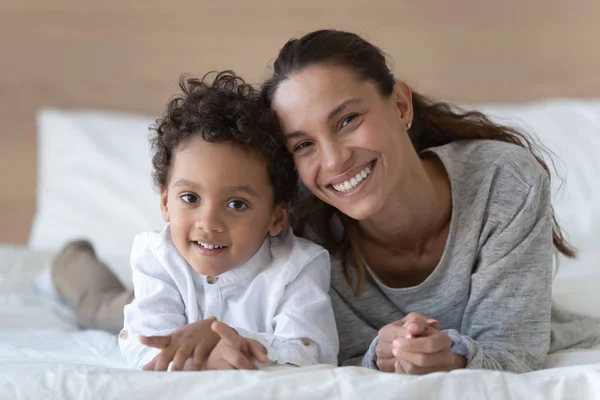 Glücklich lächelnde junge Frau liegt mit Sohn im Bett. — Stockfoto