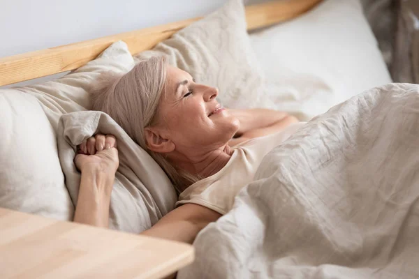 Satisfied middle-aged woman lying in bed enjoy early morning — Stock Photo, Image