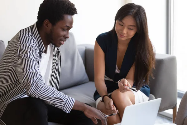 Colegas africanos asiáticos que usan aplicaciones empresariales en computadoras trabajando juntos —  Fotos de Stock