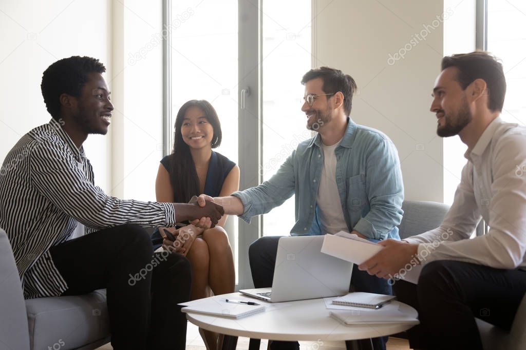 Multiethnic staff meet client boss shake hands express respect