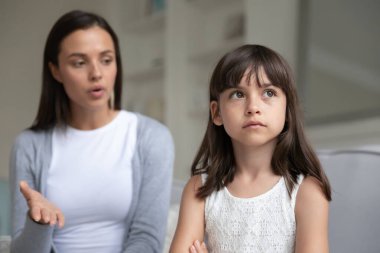 Discontented young mother scolding little daughter expresses displeasure clipart