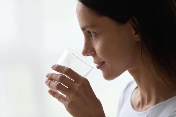 Zbliżenie twarzy pięknej kobiety po trzydziestce trzyma szklankę wody — Zdjęcie stockowe