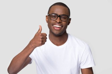 Sağlıklı beyaz gülüşlü Afro-Amerikalı adam başparmağını kaldırıyor.