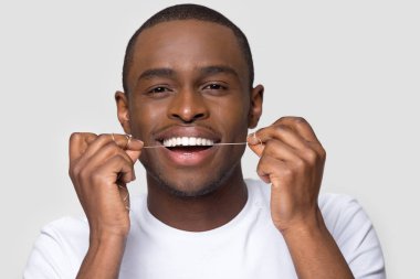 Diş ipi kullanan sağlıklı gülüşü olan mutlu Afrikalı Amerikalı adam.