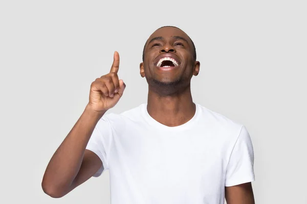 Веселый смеющийся афроамериканец показывает пальцем вверх — стоковое фото