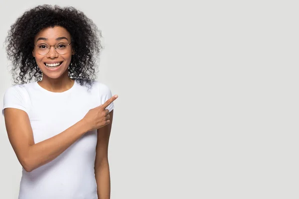 Smiling African American woman in glasses pointing finger at copy space — Stock Photo, Image