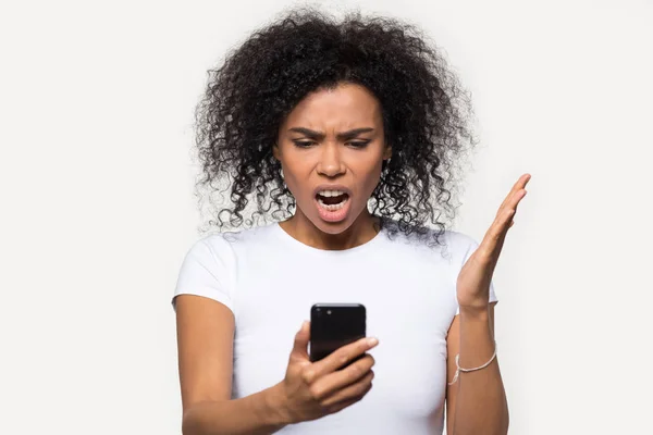 Mujer afroamericana enojada mirando el teléfono, molesta por el spam — Foto de Stock