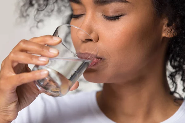 Жаждущая афроамериканка пьет чистую минеральную воду вблизи — стоковое фото