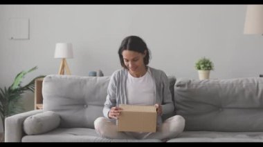 Gülümseyen tatmin olmuş kadın müşteri posta paketini açıyor.