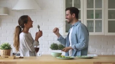 Genç mutlu çift şarkı söylüyor. Mutfakta sağlıklı yemek hazırlıyorlar.