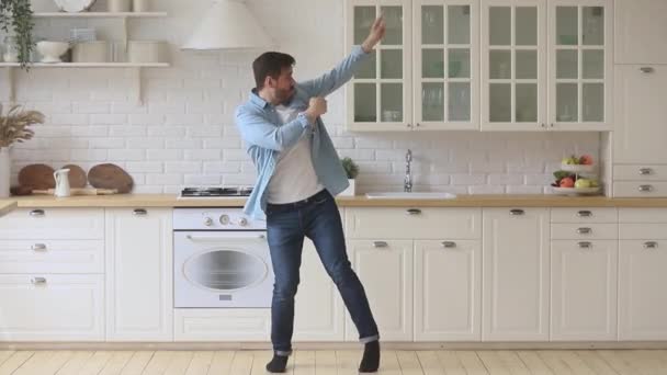 Activo joven despreocupado disfrutando de la danza divertida de pie en la cocina — Vídeo de stock