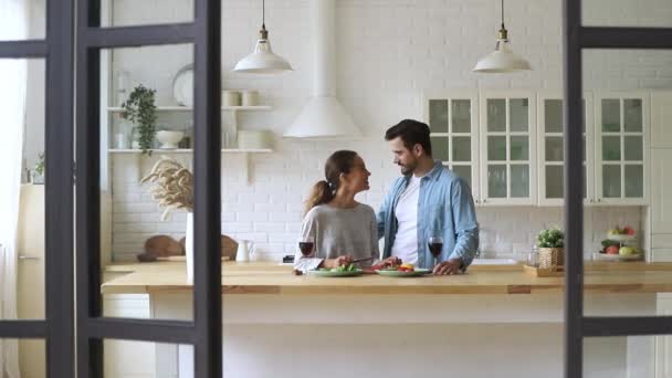 Feliz pareja joven corte ensalada cocinar juntos en la cocina moderna — Vídeos de Stock