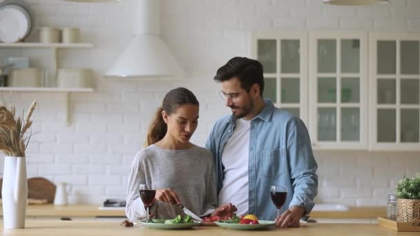 Gelukkig romantisch paar koken praten klinkende wijn bril in keuken — Stockvideo