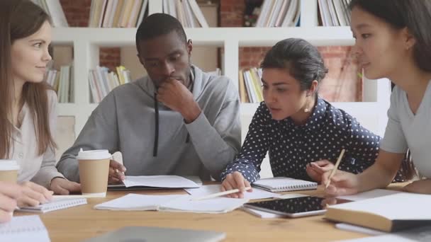 Amigos de raza mixta concentrados que trabajan en un proyecto de investigación . — Vídeo de stock