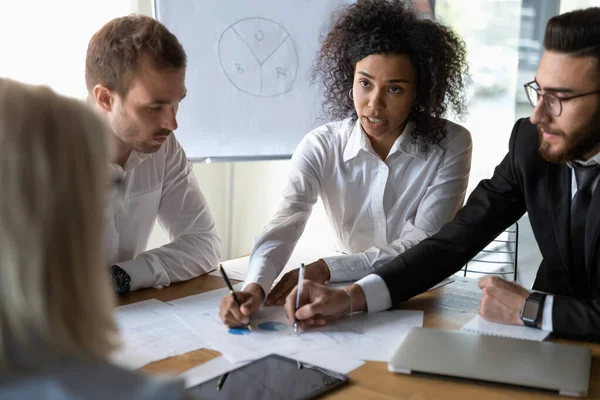 Colegas multiétnicos discutiendo el papeleo financiero en la sesión informativa — Foto de Stock