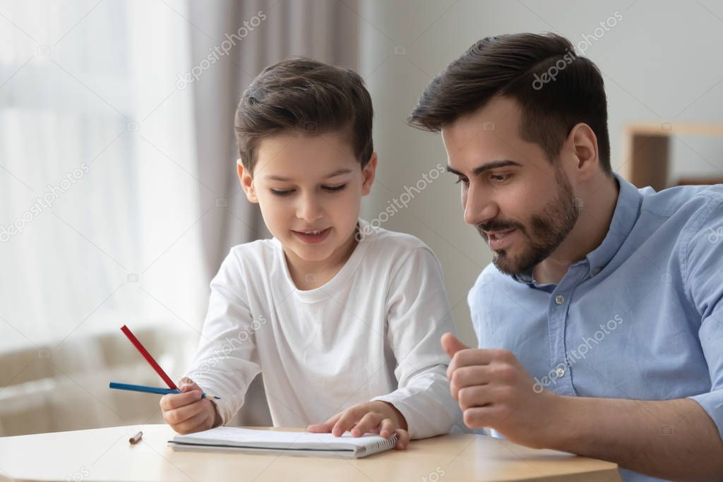 Father helps to little son teaches to draw with pencils
